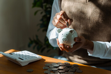 Young man putting coin into piggy bank , Saving money wealth and financial concept.