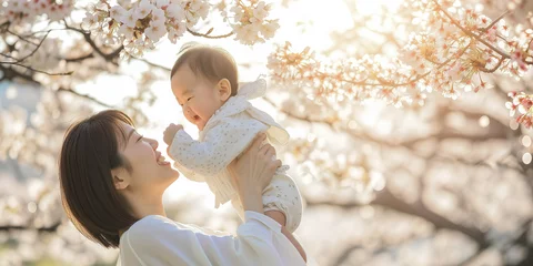 Tuinposter 桜の咲く公園で赤ちゃんを抱える母親 © JIN KANSA