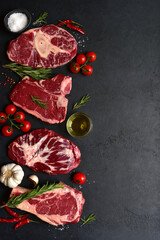 Different types of raw marbled beef steaks : T-bone, ossobuko, spider and rib eye with ingredients for cooking. Top view with copy space.