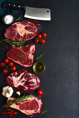 Different types of raw marbled beef steaks : T-bone, ossobuko, spider and rib eye with ingredients for cooking. Top view with copy space.