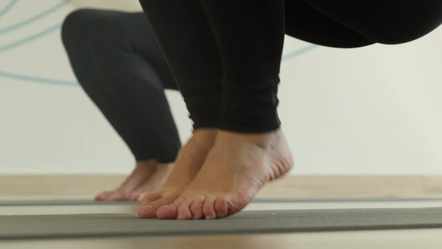 Feet of women practicing fortifying yoga moves in aero yoga studio. Athletic women raise bent legs toward abdomen to fortify pelvic muscles