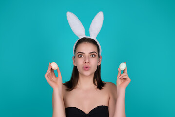 Portrait of young girl feeling happy, celebrating Easter, wear rabbit ears hold painted eggs. Young...
