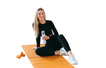 Cheerful blonde caucasian young woman in black sportswear sits on yoga mat with Bottle of water against transparent background. Satisfied Swedish girl trains at sport club, break time