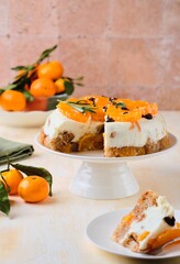 Jelly cake with a creamy part, spiced cupcake and tangerine on a white cake stand on a light concrete background. Dessert recipes