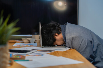 Side view of businessman heavy workload sleep on laptop at office desk with finance sheet...