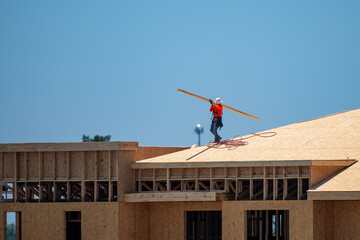 Roofing on roof. Builder roofer install new roof. Construction worker roofing on a large roof apartment building development. Roofer carpenter working on roof structure construction site.