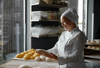 Experienced skilled woman baker forming baguettes working in bakery