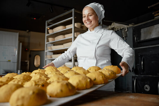 Satisfied positive woman baker in uniform at craft bakery workshop
