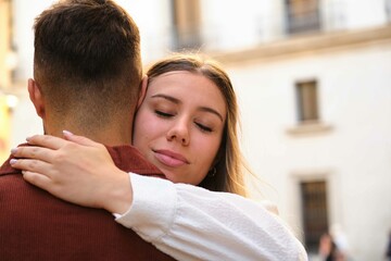 Happy young Caucasian couple hugging at street. Love and romanticism.