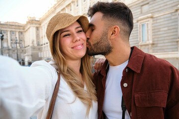 Young Caucasian couple taking a selfie while kissing and sightseeing the city of Madrid, Spain.