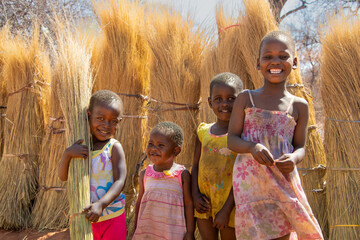 family of African children playing together in front of thatch grass, village life, sunny day of...
