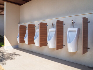 modern clean public restroom with tiles. Line of men's white urinals in public restrooms.