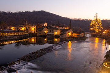 Fototapeta premium Festive Lights Reflect: Christmas 2024 in Borghetto sul Mincio. Bright reflections on calm waters create a enchanting nocturnal spectacle of celebration and magic