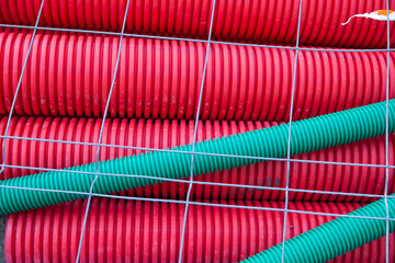 Red plastic corrugated pipes covered with steel mesh.