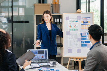 Group of young Asian business people discussing business plan at modern startup in creative business discussing work