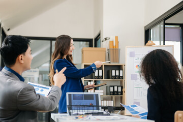 Group of young Asian business people discussing business plan at modern startup in creative business discussing work