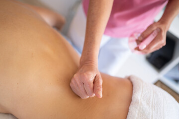 Crop masseuse massaging back of client in clinic