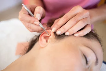 Foto auf Alu-Dibond Schönheitssalon Crop chiropractor massaging ear of woman during auriculotherapy in beauty salon
