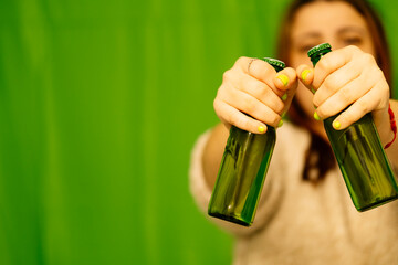 A girl holding two green beer bottles.