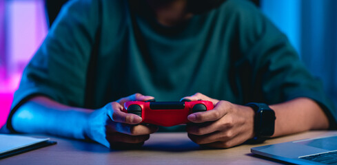 Young asian woman enjoy playing video game by talking on headphones in living room at night.