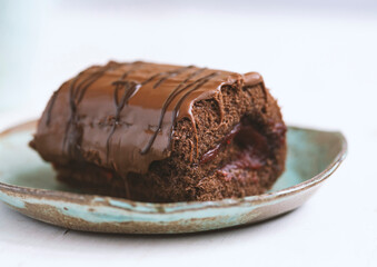 Chocolate cake with blackcurrant in ceramic plate on white wooden background.close up