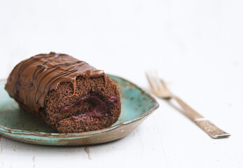 Chocolate cake with blackcurrant in ceramic plate on white wooden background.close up
