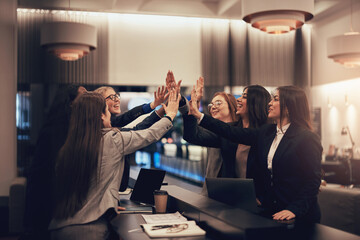 Smiling businesswomen high-fiving during a meeting in a hotel lobby