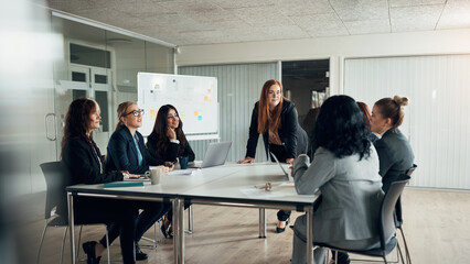 Smiling executive and a group of businesswomen talking during a boardroom meeting