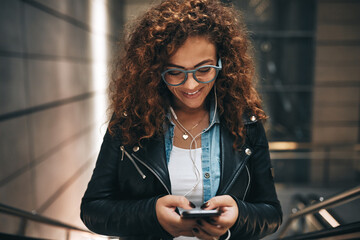 Young woman standing on a metro escalator reading text messages