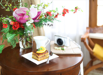 Chocolate cake, tea, tablet computer, camera and bouquet of blossom spring flowers