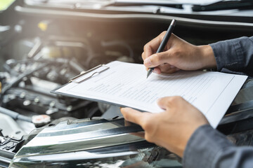 Auto check up and car service shop concept. Mechanic writing job checklist to clipboard to estimate repair quotation to client at workshop garage. - obrazy, fototapety, plakaty