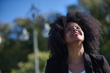 Portrait of young, beautiful, black woman with afro hair, wearing jacket, looking at the sky, grateful, praying. Concept gratitude, praying, current, modern.