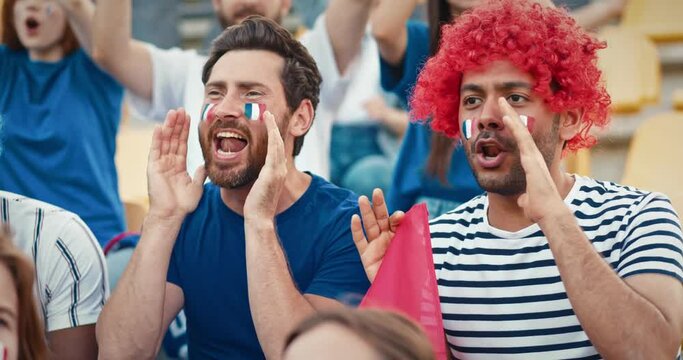 Mixed-race people shouting together words of support. Fans having painted face with French flag. Supporting their favourite team in championship. Team spirit. Competition concept.