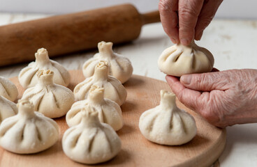 cook making khinkali, dumplings, meat in the dough cooking with hands. Juicy meat in a dough with...
