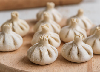 Raw frozen khinkali  on wooden table. Process preparation georgian meal. food concept.