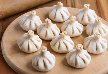 Raw frozen khinkali  on wooden table. Process preparation georgian meal. food concept.