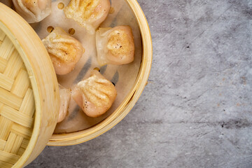Homemade dumplings dim sum close-up in a bamboo steamer box on table. Horizontal top view from above