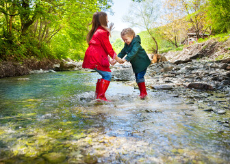 Children wearing rain boots jumping into a mountain river