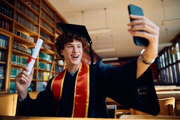 Cheerful graduate student taking selfie with cell phone.