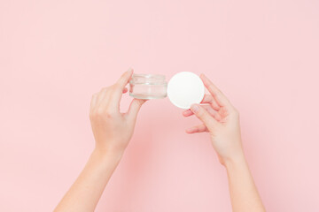 Hand holding glass clear cosmetics jar for face or skin cream. Package for cosmetic beauty product, luxury makeup container