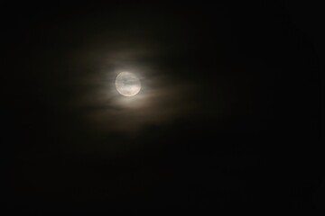 Full moon over dark black sky at night. Mysterious concept with clouds, fog and moon.