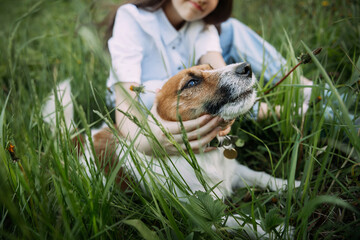 A young woman sitting on grass and holding a brown dog. 4929