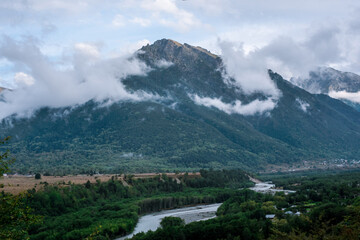 River in the mountains region and foggy mountain peaks in the background