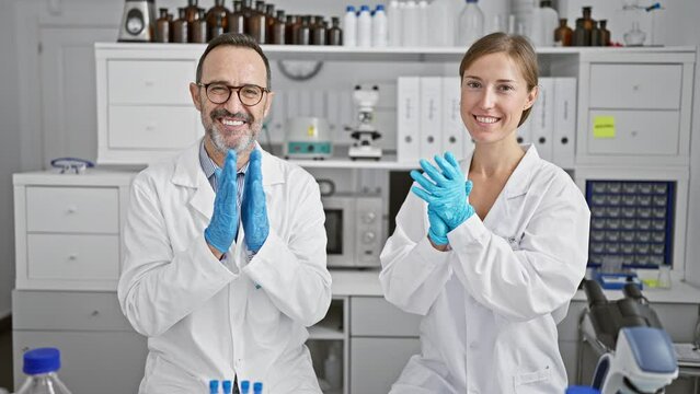 Two smiling scientists clapping hands in applause, celebrating major research breakthrough in their lab