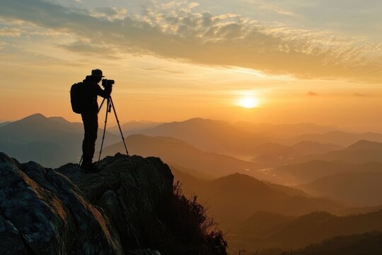 A man standing on top of a mountain, holding a camera. This picture can be used to depict adventure, travel, photography, or capturing beautiful landscapes