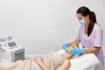 Beautiful woman getting face massage treatment in beauty salon. copy space