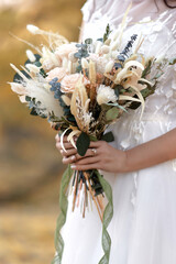 hands of the bride holding beautiful autumn bouquet outdoor