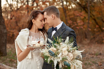 bride and groom on the nature in autumn . wedding couple with cake outdoor