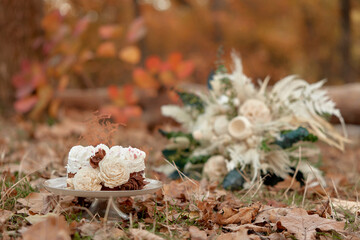 wedding cake with flowers on autumn fallen leaves outdoor