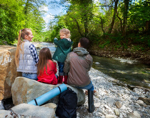 Happy young family with two little daughters near the mountain river